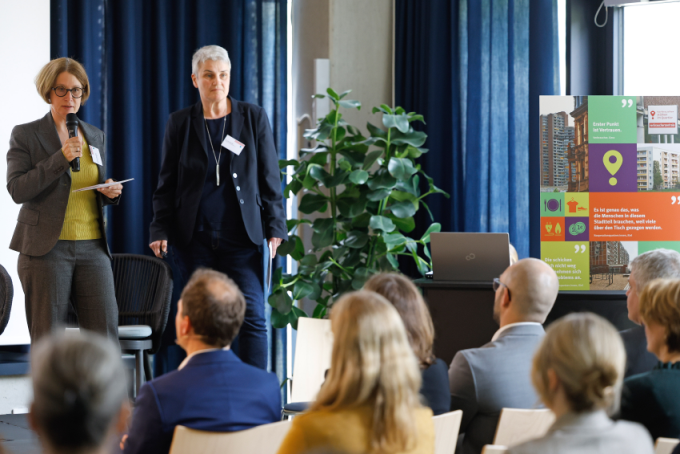 Dr. Iris van Eik und Carina Lichtenberg halten stehend ihren Vortrag