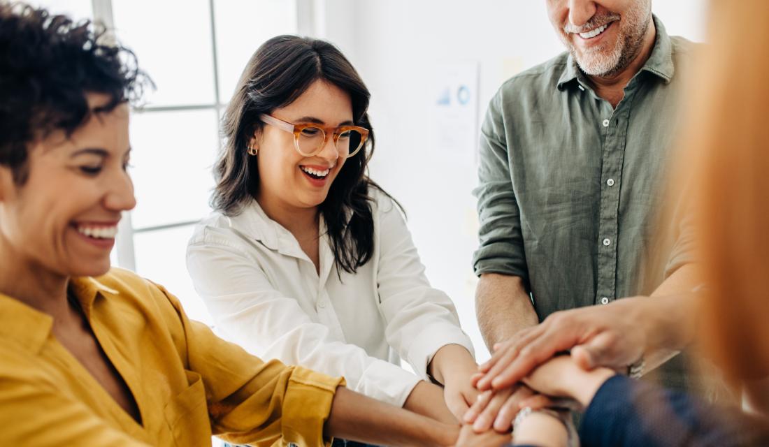 Gruppe von Menschen steht zusammen und hält die Hände in der Mitte zusammen