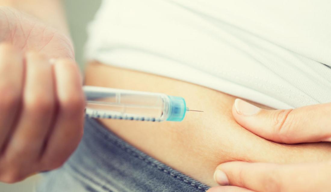 Jemand setzt sich eine Spritze an den Bauch