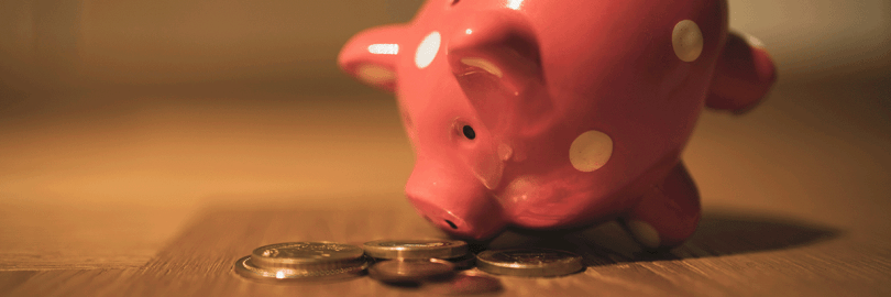 Sparschwein mit Münzen auf Holztisch