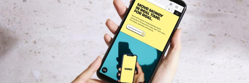 Zwei Hände halten ein Smartphone, auf dem Display ist die Internetseite von Wero zu sehen