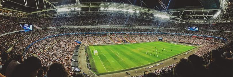 Ein Fußballstadion mit Spielern auf dem Feld und Zuschauern auf den Rängen