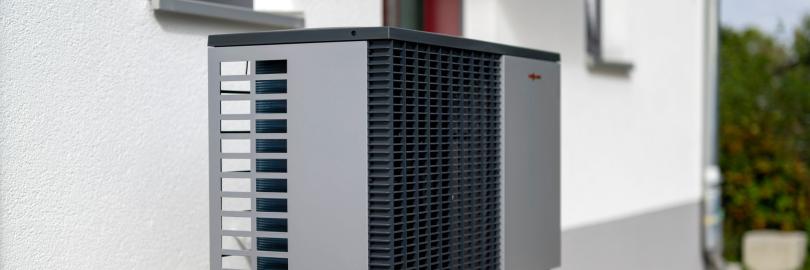 Eine Wärmepumpe, die vor einem offensichtlichen Einfamilienhaus steht