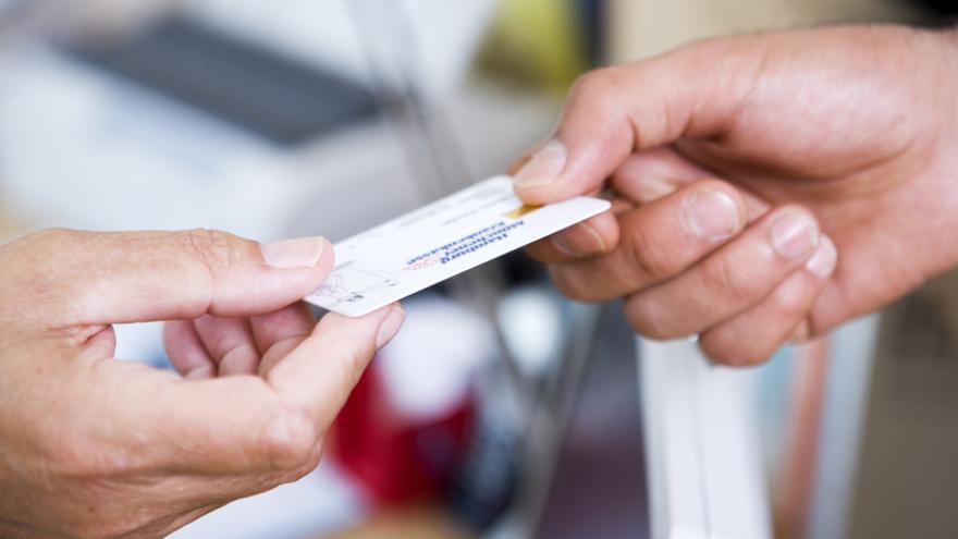 Hand überreicht die Versichertenkarte der Krankenkasse beim Arzt