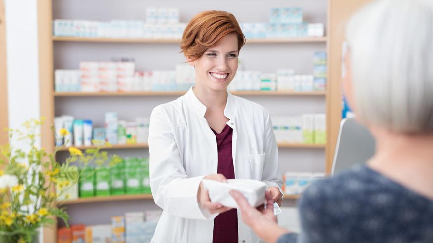 Ältere Dame kauft Medikamente in der Apotheke mit freundlichen Apothekerin