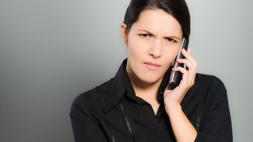 Eine Frau telefoniert und schaut dabei ernst.