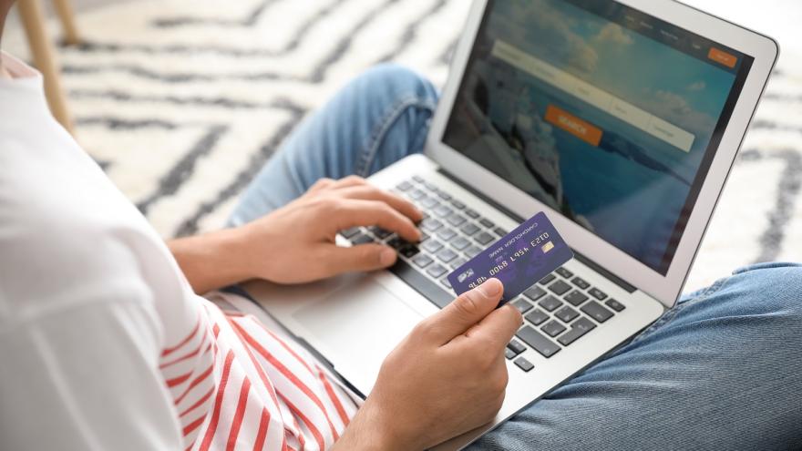 Ein Mann bucht einen Flug am Laptop und benutzt dafür eine Kreditkarte