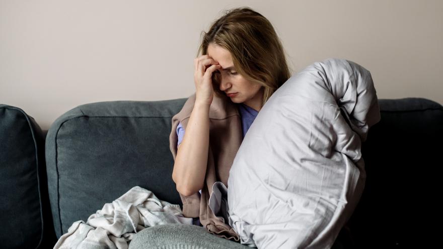 Eine Frau mit Long-COVID sitzt erschöpft auf einem Sofa