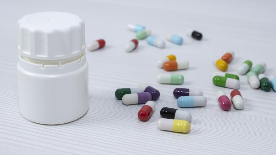 Tablettenkapseln liegen auf einem Tisch, daneben eine geschlossene Pillendose