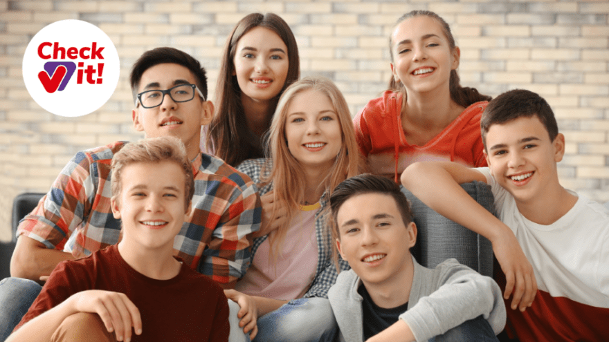 Junge Personen sitzen in einer Gruppe zusammen und lächeln. Links ist das Verbraucherchecker-Signet zu sehen.