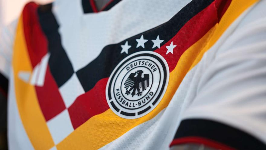 Nahaufnahme des weißen DFB-Heimtrikots für die WM 2026 mit dem runden Logo des Deutschen Fußball-Bundes und vier Weltmeister-Sternen.