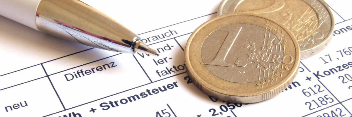 Stift und Münzen liegen auf einer Stromrechnung.
