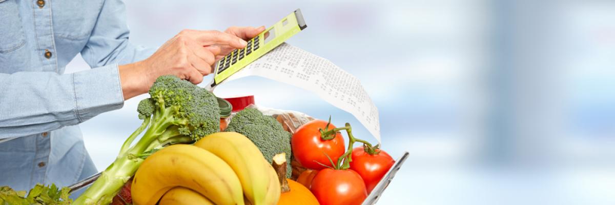 Jemand mit Gemüse im Warenkorb und Taschenrechner