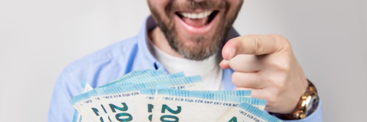 Lachender Mann mit Geldscheinen in der Hand