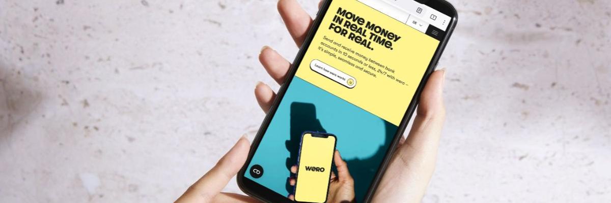 Zwei Hände halten ein Smartphone, auf dem Display ist die Internetseite von Wero zu sehen