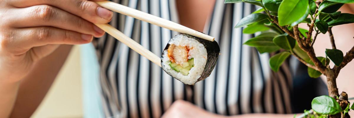 Eine Person isst Sushi mit Stäbchen